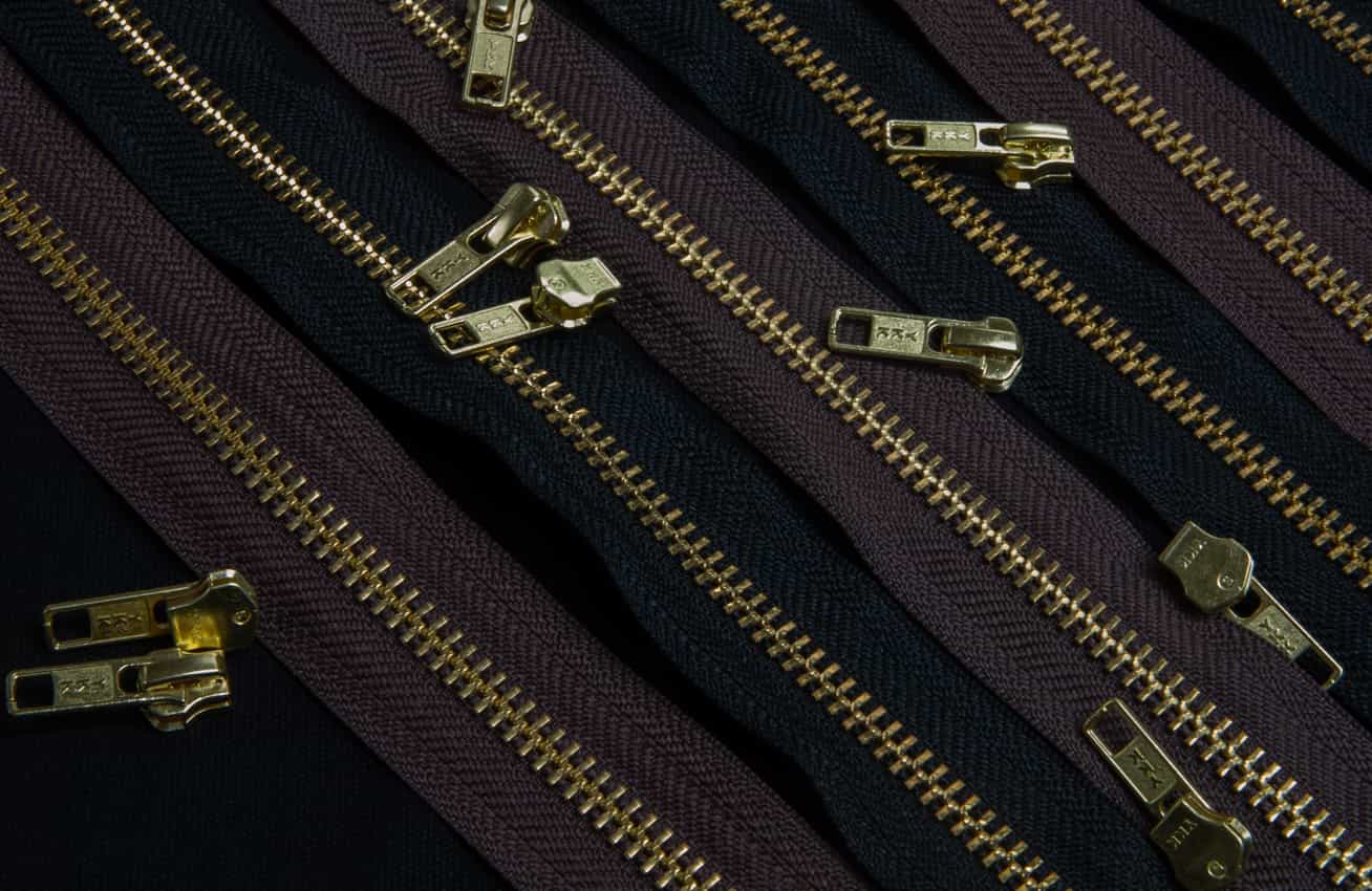 Brown and black zipping with brass zip slides laid on top